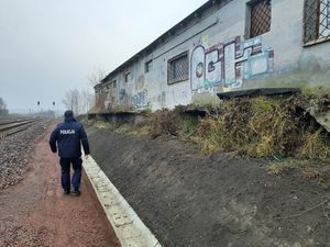 Zdjęcie przedstawia idącego policjanta przy rozwalonym budynku na którym sa namalowane garffiti.